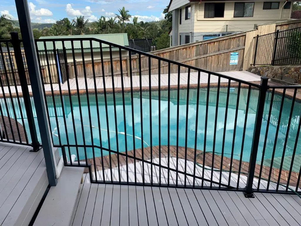 Black aluminium pool fence with a raked panel following deck stairs