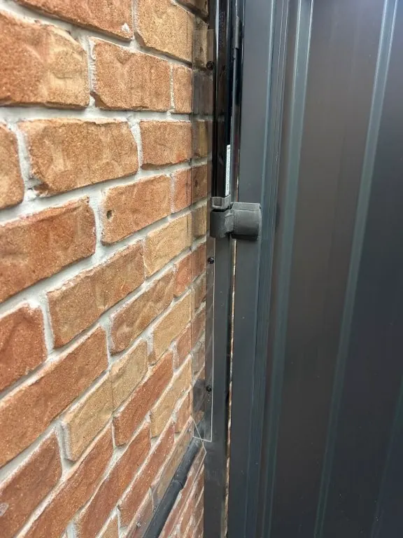 Close-up of a self-latching pool gate latch on a grey aluminium gate