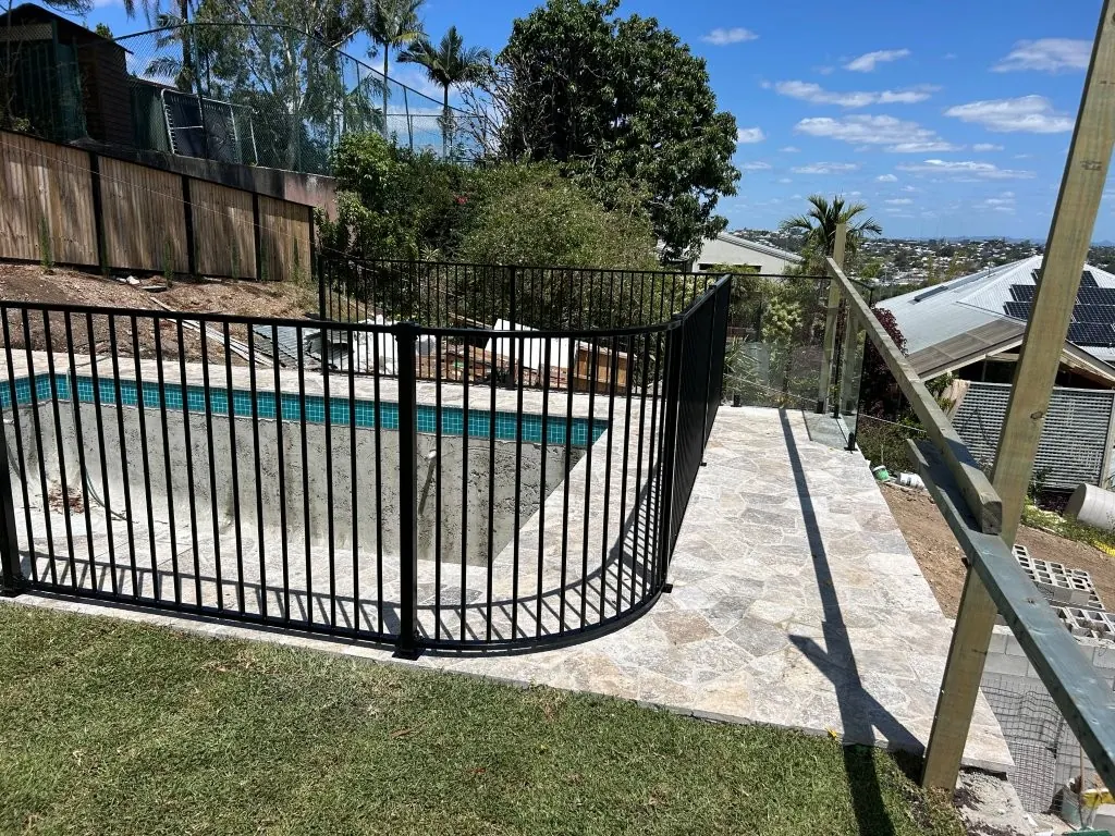 Black aluminium pool fence with curved panels on a sloping block