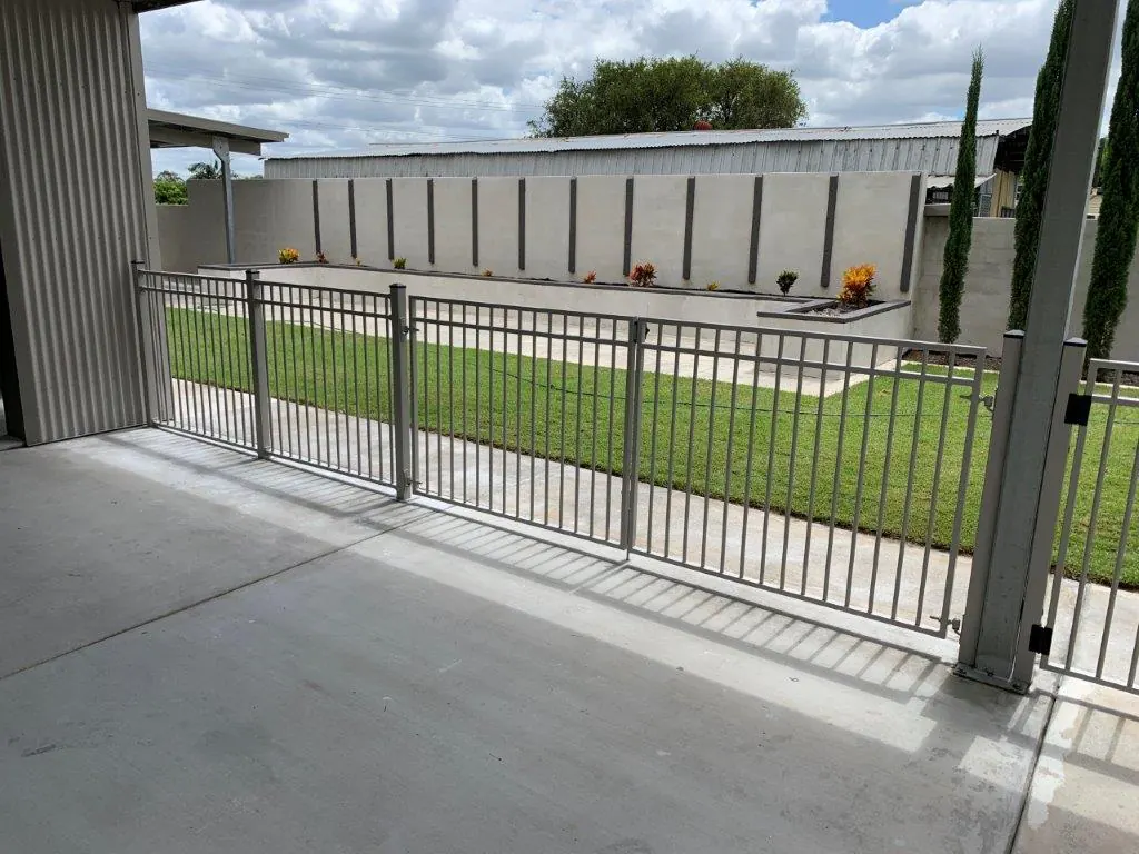 Grey aluminium pool fence and gate beside a lawn and courtyard